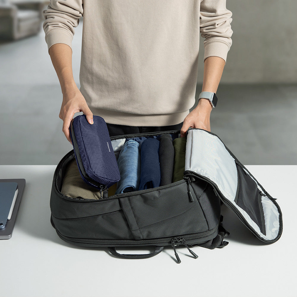 The Tomtoc T77 backpack open flat, showing its clamshell layout and travel pouches